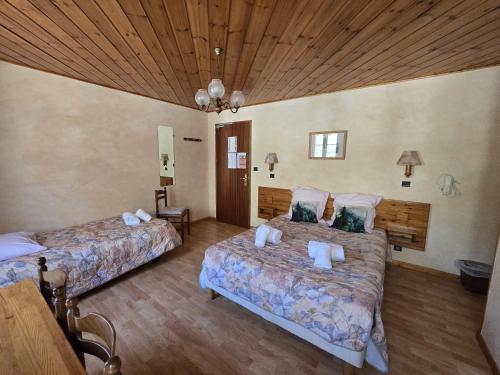 a bedroom with two beds and a wooden ceiling at Les Touristes in Abondance