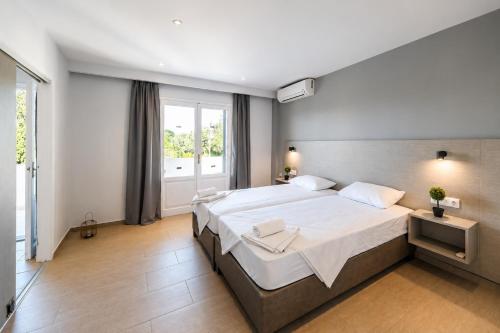 a bedroom with a large bed and a window at Nikos Villas - Poolside Getaways in Kavos, Corfu in Kavos