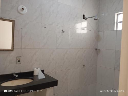a bathroom with a shower with a sink and a mirror at EcoRupestre Hostel & Receptivo in São Raimundo Nonato