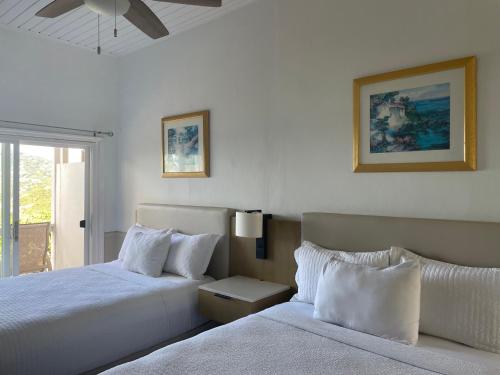 a white bedroom with two beds and a window at Queen Deluxe Double at Boundless Bliss Hotel in Raphune