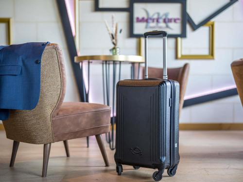 a suitcase sitting on the floor next to a chair at Mercure Bords de Loire Saumur in Saumur