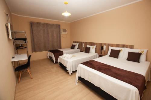 a hotel room with two beds and a desk at Gru Inn Hotel in Guarulhos