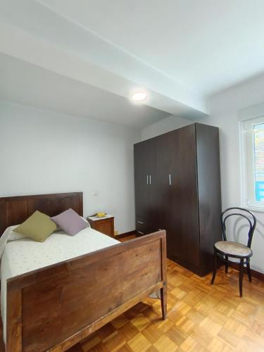 ein Schlafzimmer mit einem Bett, einem Schrank und einem Stuhl in der Unterkunft A Esteva in Orol