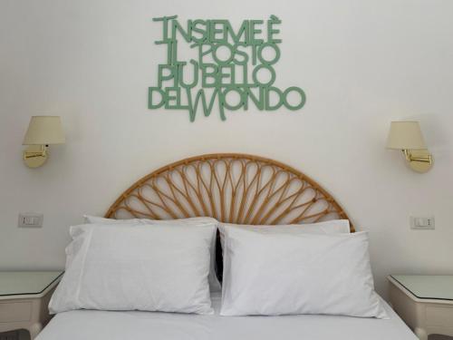 a bed with white pillows and a sign on a wall at 2Steps Capri - central holiday house in Capri