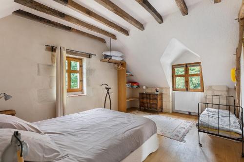 a bedroom with a white bed in a room with wooden ceilings at Le Trianon Isabelle de Maillé - in Cravant-les-Coteaux