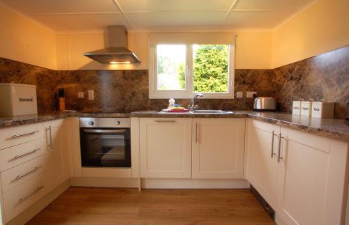 a kitchen with white cabinets and a window at Glen Affric Holiday Park in Cannich