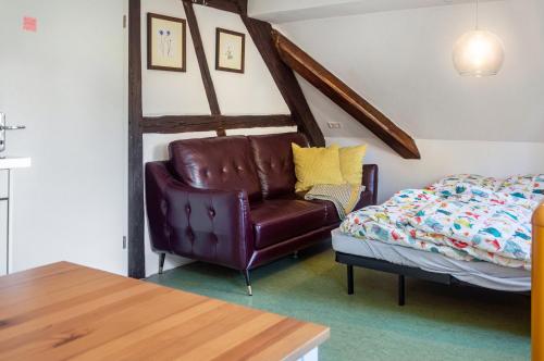 a living room with a leather chair and a bed at Alte Schmiede Ellrichshausen 2 in Satteldorf