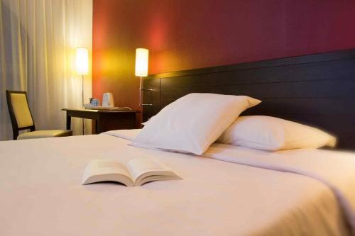 a book laying on top of a bed with pillows at Ibis Styles Metz Centre Gare in Metz