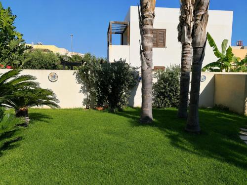 a yard with palm trees and a building at Villa Favignana in Favignana