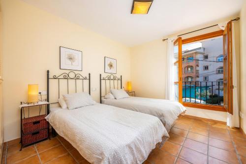 two beds in a room with a window at Cala Pi Two in Cala Pi