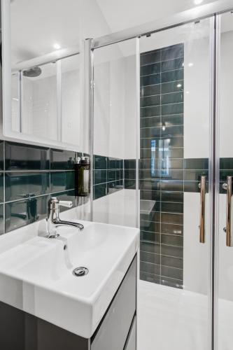 a white bathroom with a sink and a shower at Upper Victoria in London