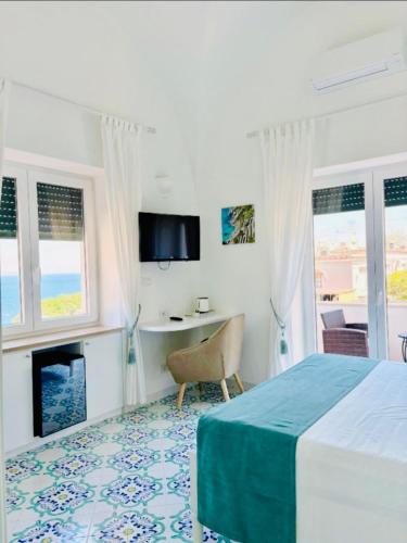 a bedroom with a bed and a desk and windows at B&B L'Agapanto in Capri