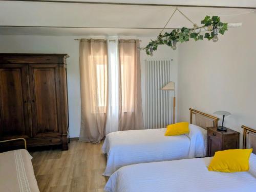 ein Schlafzimmer mit zwei Betten mit weißen Laken und gelben Kissen in der Unterkunft Appartamento in Monferrato di Dominga in Portacomaro