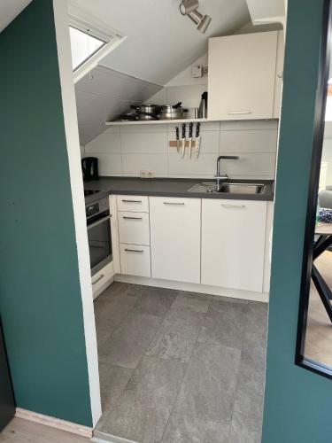 a kitchen with white cabinets and a sink at Moderne Ferienwohnung mit Balkon und Klima in Neufraunhofen