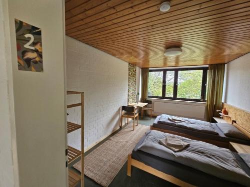 a bedroom with two beds and a wooden ceiling at Gästehaus am Sternberg in Gomadingen