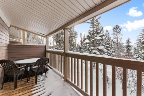 a balcony with a table and chairs and snow covered trees at Rockridge #51 in Breckenridge