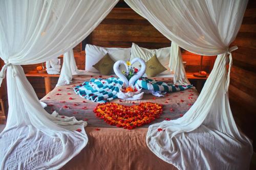 a bed with two swans and a heart of flowers at Mamaras Guest House in Nusa Penida