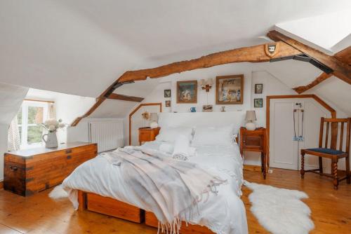 a bedroom with a large bed with white sheets at Cheesemans Cottage in Grimstone