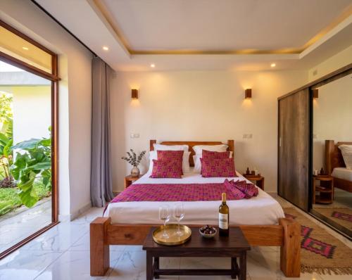 a bedroom with a large bed with purple pillows at Casa Samara in Diani Beach