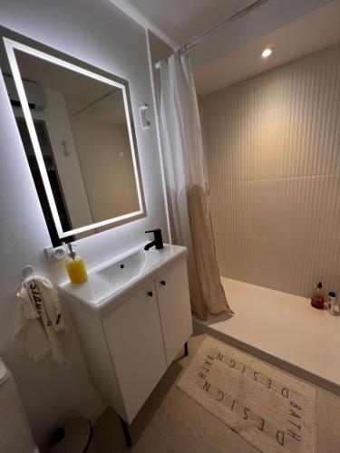 a white bathroom with a sink and a mirror at Cozy independent apartment in Mornant