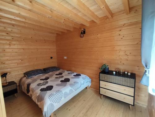 a bedroom with a bed in a wooden room at Cabane des Roches à 2 min de Vulcania - Calme et Nature in Saint-Ours