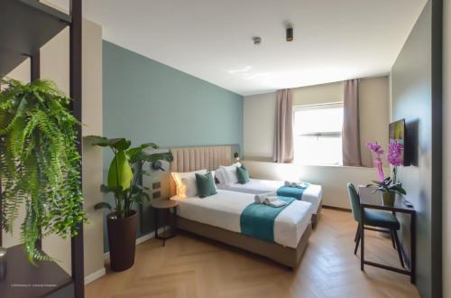 a bedroom with a bed and a chair and plants at CP Hotels - Central in Milan