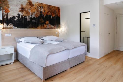 a bedroom with a bed with a painting on the wall at Hotel Băile Bughea in Bughea de Sus