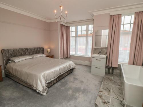 a bedroom with a bed and a tub and a sink at Ruby's Retreat in Filey