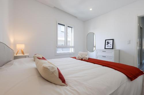 a white bedroom with a large white bed with a red blanket at Villa Piscina Privada 3 Quartos 8 Hóspedes in Fernao Ferro