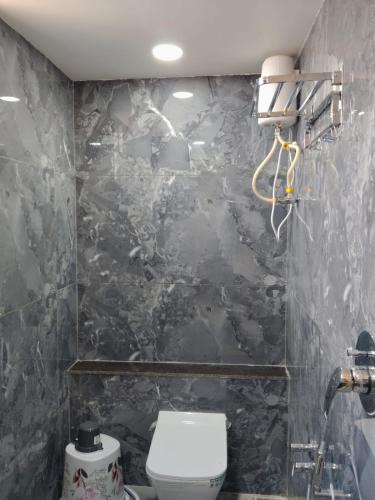 a bathroom with a toilet and a black marble wall at Hotel Sun City in Kalol