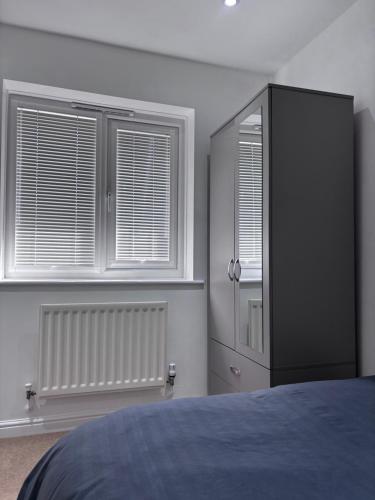 a bedroom with a black cabinet and two windows at Private Hydro Spa Pool, Dbl Bedrm & Bathrm - Other areas part private shared lived-in home in Bickershaw