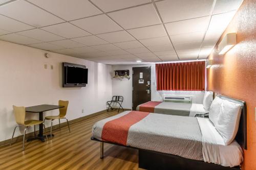 a room with two beds and a desk and a tv at Hotel Elizabeth Near Newark Liberty International Airport New Jersey in Elizabeth