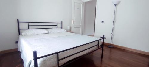 a white bed in a room with a lamp at Alloggio Maia 2 in Biella