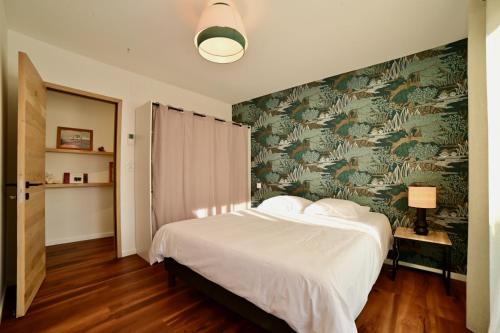 a bedroom with a bed with a green and white wallpaper at Le Clos des Izards in Périgueux
