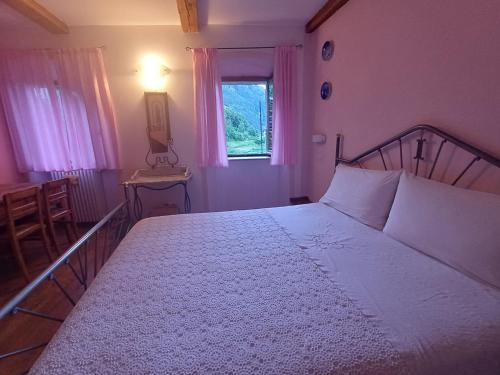 a bedroom with a large white bed with a window at Rooms Alpe Veglia-Varzo in Varzo