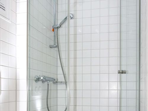 a shower in a bathroom with white tiles at ibis budget Augsburg City in Augsburg