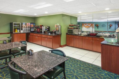 a restaurant with tables and chairs and a kitchen at Ramada Limited Decatur in Forsyth