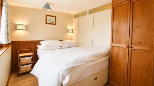 a small bedroom with a bed with white sheets at C19 Old Range, Riviere Towans in Hayle