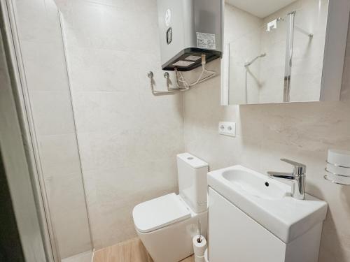 a white bathroom with a toilet and a sink at Apartaments Angelina in La Pobla de Segur