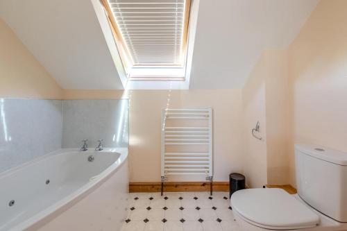 a bathroom with a tub and a toilet and a window at 1 Bed in Bideford oc-labdr in Woolfardisworthy