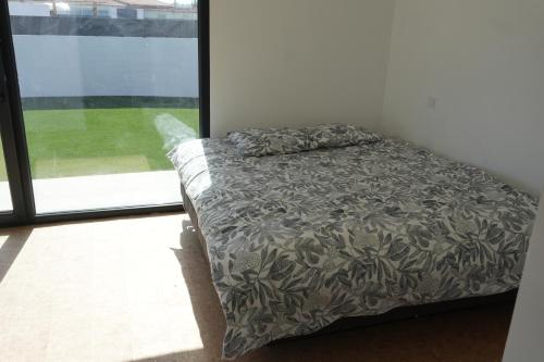 a bed in a room next to a window at IROC Private Garden in Quinta do Anjo
