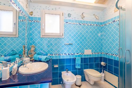 a blue tiled bathroom with a toilet and a sink at Blue Moon in Castelsardo