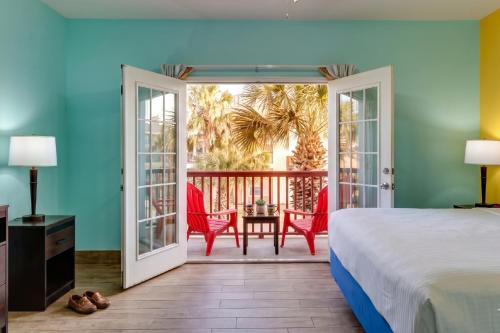 a bedroom with a bed and a balcony with a table and chairs at The Island Hotel Near Beach Port Aransas in Port Aransas