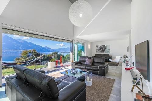 a living room with a couch and a large window at Villa Mondacce with Jacuzzi & Lake Views in Minusio