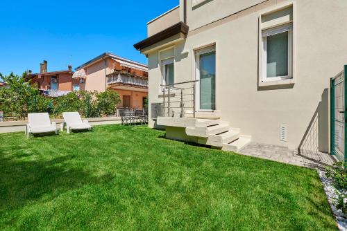 a backyard with green grass and white chairs at Sand Beach House - Host Solution in Cavallino-Treporti