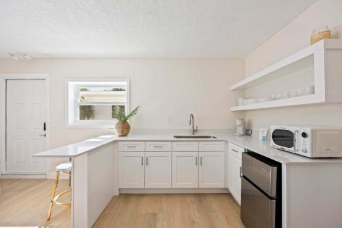a white kitchen with a sink and a microwave at Anchor House in Cocoa Beach