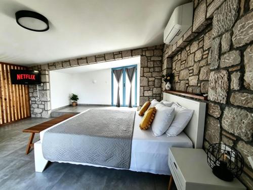 a bedroom with a bed and a stone wall at Anasa Rustic Villa in Kolymbia