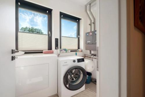 a washing machine in a bathroom with two windows at Design-Apartment mit Garten in Langenbach