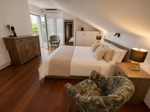a bedroom with a large bed and a chair at Villa Magnetic in Baošići