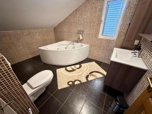 a bathroom with a tub and a toilet and a sink at Villa Magnetic in Baošići
